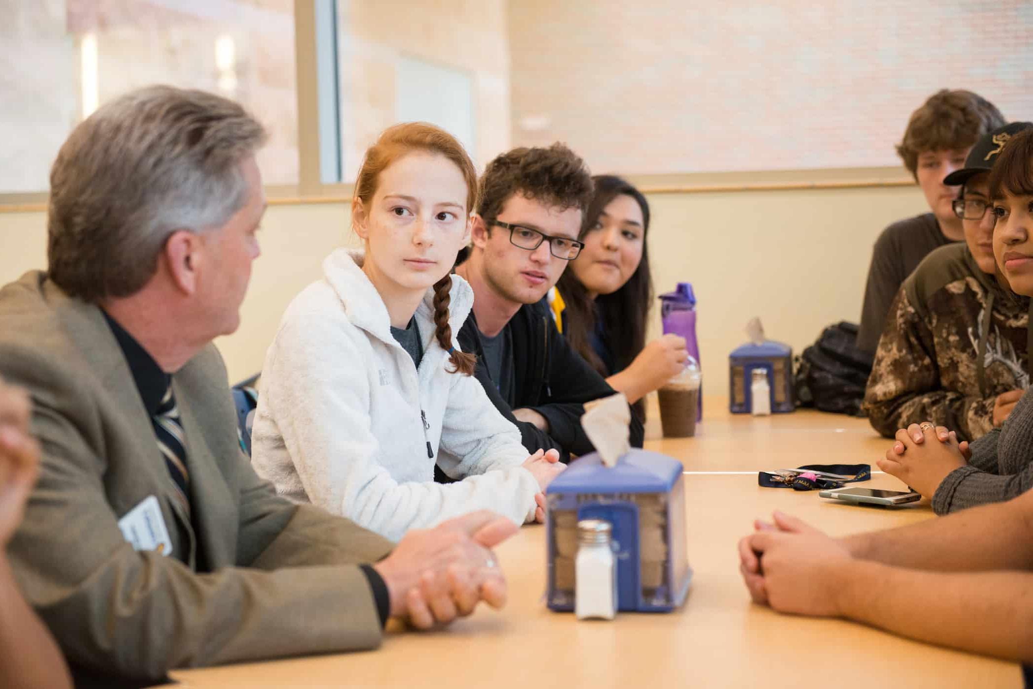 Professor talking with students at long table